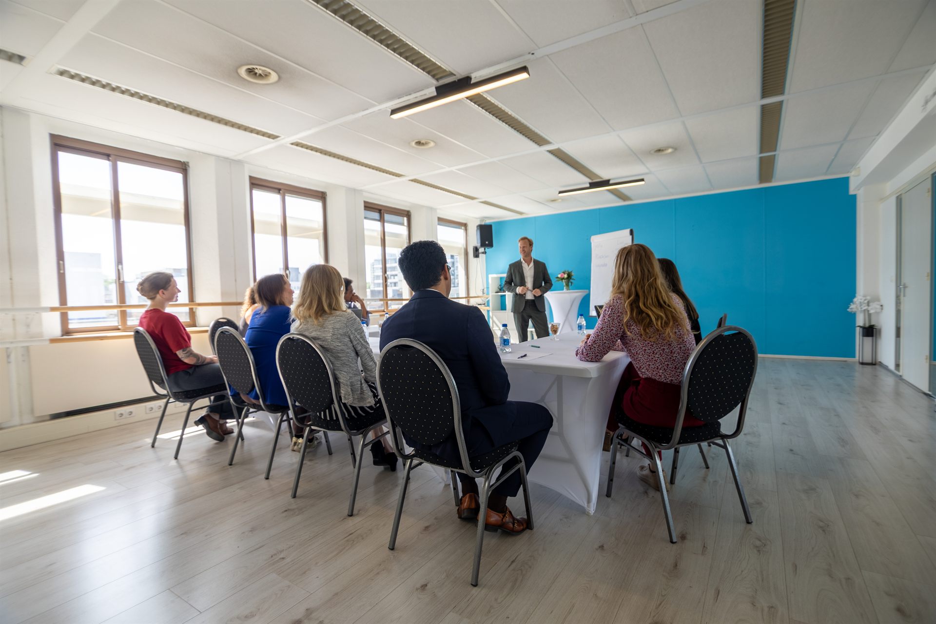 Bijeenkomst in een lichte zaal, spreker bij de presentatiewand